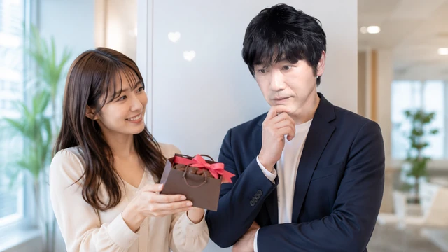 バレンタインのチョコを差し出す女性を前に、本命なのか気になって考え込む男性