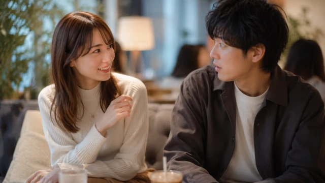 カフェで女性から話しかけられ、少し驚きながら振り返る男性のイメージ